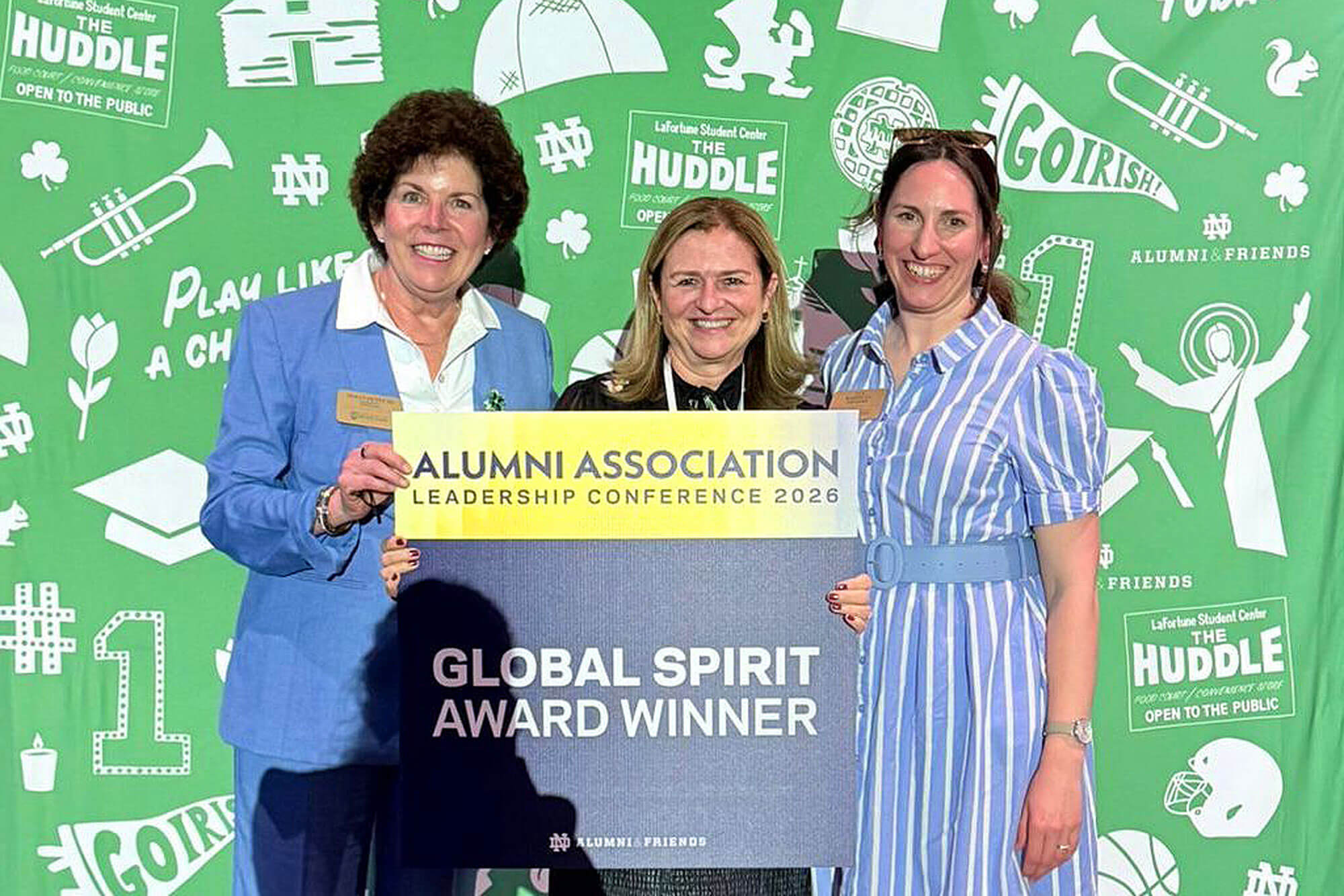 Three smiling women hold a large sign: "Alumni Association Leadership Conference 2026 Global Spirit Award Winner."