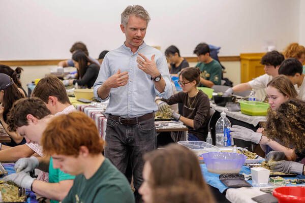 Ceramics expert Coleton Lunt speaks while walking among the tables of participants.