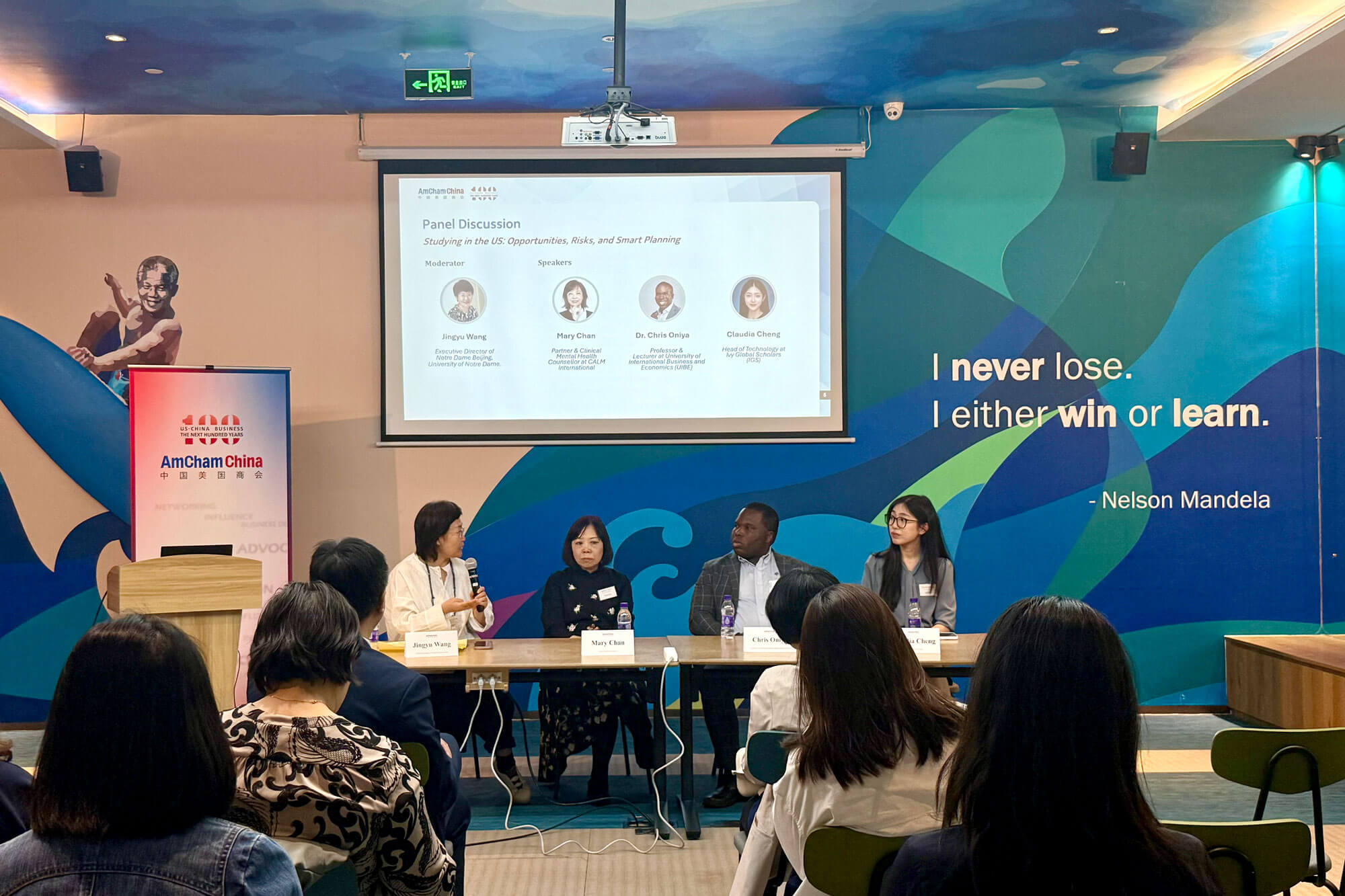 Jingyu Wang, Notre Dame Beijing Executive Director, speaks on a diverse panel about US study. Audience listens; screen shows names.